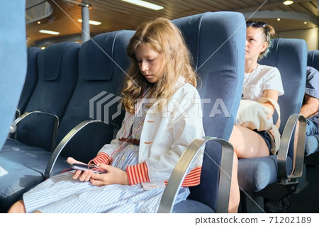 Girl child using smartphone while sitting inside ferry Girl child using smartphone while sitting inside ferry 71202189