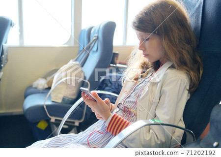Girl child using smartphone while sitting inside ferry Girl child using smartphone while sitting inside ferry 71202192