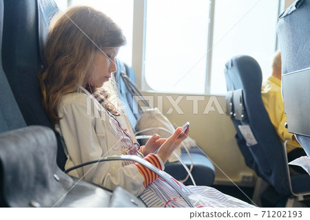 Girl child using smartphone while sitting inside ferry Girl child using smartphone while sitting inside ferry 71202193
