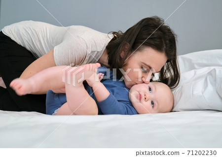 Young mother lovingly kisses her son toddler Young mother lovingly kisses her son toddler 71202230