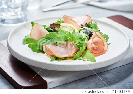 Salad with ham and arugula on white plate 71203179