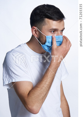 Young man wearing adjusting his medicine mask 71203335