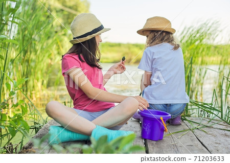Children two girls together playing with water on lake on wooden pier in reeds 71203633
