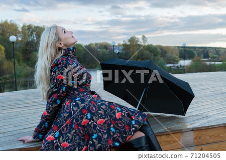 A girl with a black umbrella sits on a wooden staircase, a lot of puffy clouds on the stage. with charismatic appearance A girl with a black umbrella sits on a wooden staircase, a lot of puffy clouds on the stage. with charismatic appearance 71204505