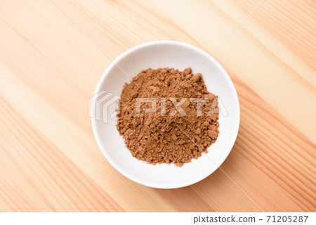 Cinnamon powder on a plate on a wood grain table 71205287