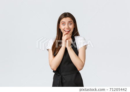Small business, employees and coffee shop concept. Excited happy saleswoman looking temptation and rejoice at product. Cheerful coffee worker hear good news amused Small business, employees and coffee shop concept. Excited happy saleswoman looking temptation and rejoice at product. Cheerful coffee worker hear good news amused 71205442