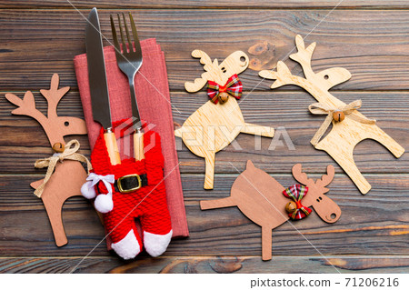 New year set of fork and knife on napkin. Top view of christmas decorations and reindeer on wooden background. Close up of holiday family dinner concept New year set of fork and knife on napkin. Top view of christmas decorations and reindeer on wooden background. Close up of holiday family dinner concept 71206216
