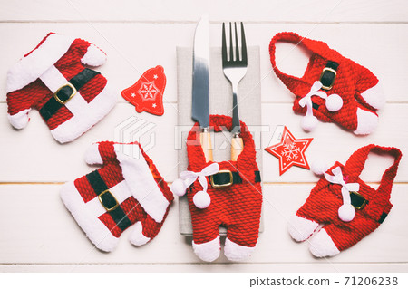 Festive set of fork and knife on wooden background. Top view of new year decorations and santa clothes and hat. Close up of christmas concept Festive set of fork and knife on wooden background. Top view of new year decorations and santa clothes and hat. Close up of christmas concept 71206238