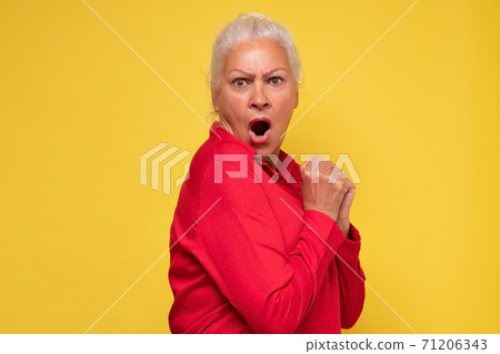 A young greedy woman hides something in her hands and looks warily forward. A young greedy woman hides something in her hands and looks warily forward. 71206343