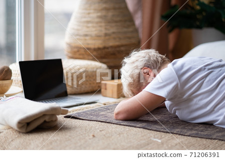 woman relaxes in yoga asana Makarasana or crocodile pose during online lesson 71206391