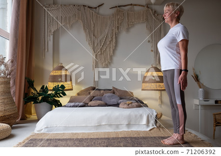 Senior woman working out indoors standing in Tadasana, Mountain Pose 71206392