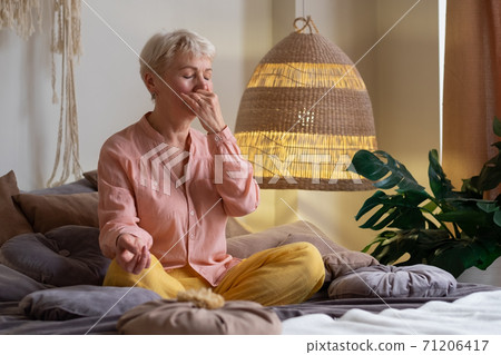 Senior woman practicing yoga at home, making Alternate Nostril Breathing exercise, nadi shodhana pranayama Senior woman practicing yoga at home, making Alternate Nostril Breathing exercise, nadi shodhana pranayama 71206417