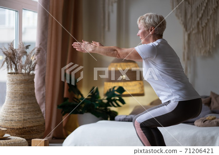 Senior caucasian woman practicing advanced yoga Chair Pose or Utkatasana Senior caucasian woman practicing advanced yoga Chair Pose or Utkatasana 71206421