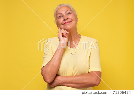 Elderly pretty woman standing daydreaming or reminiscing looking up Elderly pretty woman standing daydreaming or reminiscing looking up 71206454