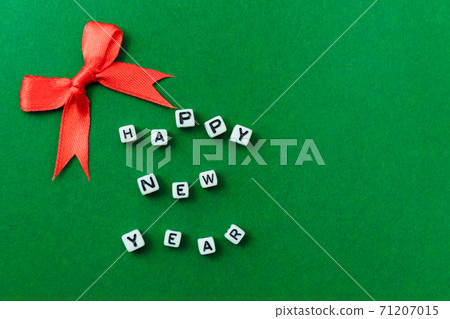 New Year concept - inscription "Happy New Year" on plastic blocks and a red Christmas bow. On a green background. Mockup for a postcard. Template for design. Copy space. Flat lay. New Year concept - inscription "Happy New Year" on plastic blocks and a red Christmas bow. On a green background. Mockup for a postcard. Template for design. Copy space. Flat lay. 71207015