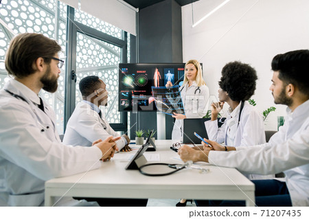 Medicine, continuing education concept. Caucasian blond woman, experienced and competent doctor, showing a presentation and speaking about new diagnostics and treatment in a seminar for colleagues Medicine, continuing education concept. Caucasian blond woman, experienced and competent doctor, showing a presentation and speaking about new diagnostics and treatment in a seminar for colleagues 71207435