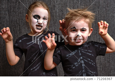 girl and boy with scary and spooky halloween makeup growls in front of a black backdrop 71208367