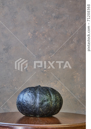 black coloured pumpkin with glitter on wooden stool in front of a brown backdrop black coloured pumpkin with glitter on wooden stool in front of a brown backdrop 71208368