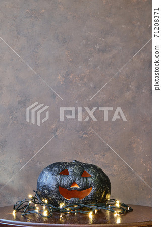 black colored pumpkin with glitter on wooden stool in front of a brown backdrop black colored pumpkin with glitter on wooden stool in front of a brown backdrop 71208371