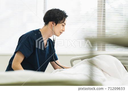 A male doctor who puts a stethoscope on a patient 71209633