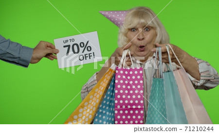 Inscription Up To 70 Percent Off appears next to grandmother. Woman celebrating with shopping bags 71210244