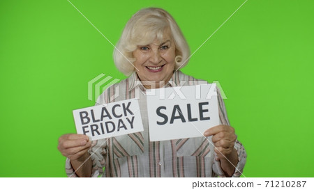 Senior grandmother showing Sale word and Black Friday inscription advertisement banners. Discounts 71210287