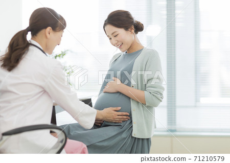 Pregnant women receiving medical examination 71210579