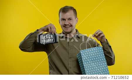 Man showing Black Friday inscription on shopping bags, smiling, satisfied with low prices purchases 71210652