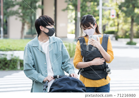 A couple walking while wearing a mask and pushing a stroller A couple walking while wearing a mask and pushing a stroller 71216980