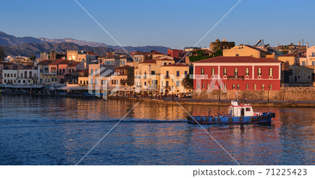 Fishing boat pass by Old Venetian harbour quay, Maritime museum of Crete in Chania, Crete, Greece. Sunrise, Cretan hills and mountains. First sun rays Fishing boat pass by Old Venetian harbour quay, Maritime museum of Crete in Chania, Crete, Greece. Sunrise, Cretan hills and mountains. First sun rays 71225423