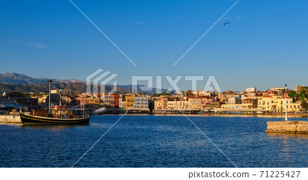 Beautiful view of Old Venetian harbour of Chania, Crete, Greece, quayside, tourist boats by piers in early morning. Cretan mountains in background. 71225427