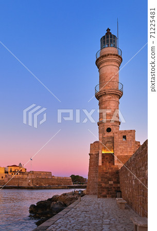 Egyptian Lighthouse of Old Venetian harbour of Chania, Crete, Greece at sunrise. Soft sky from blue to pink, vertical shot against Firka castle walls. 71225481
