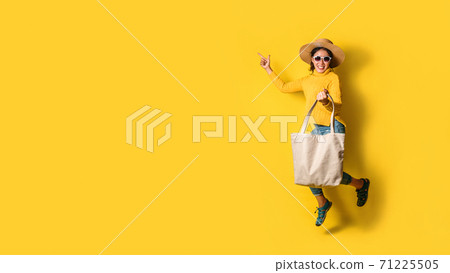 Portrait of an excited beautiful girl wearing dress and sunglasses holding shopping bags. Cheerful young woman with handbag on yellow background. Shopaholic shopping Fashion. Portrait of an excited beautiful girl wearing dress and sunglasses holding shopping bags. Cheerful young woman with handbag on yellow background. Shopaholic shopping Fashion. 71225505