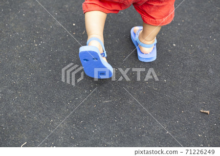 孩子走路的腳和藍色的沙灘涼鞋和黑色的背部和副本空間 孩子走路的腳和藍色的沙灘涼鞋和黑色的背部和副本空間 71226249