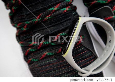 Fitness band bracelet and black fashion sneakers. Closeup, selective focus Fitness band bracelet and black fashion sneakers. Closeup, selective focus 71226601