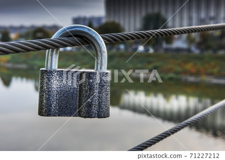 Metal padlock in front of autumn cityscape view Metal padlock in front of autumn cityscape view 71227212