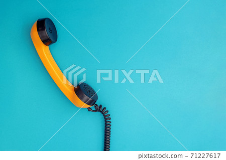Plastic orange retro tephone handset on blue 71227617
