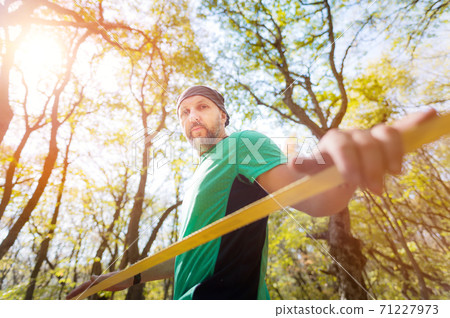 Portrait of a bearded man in age stands near a taut slackline in an autumn forest Portrait of a bearded man in age stands near a taut slackline in an autumn forest 71227973