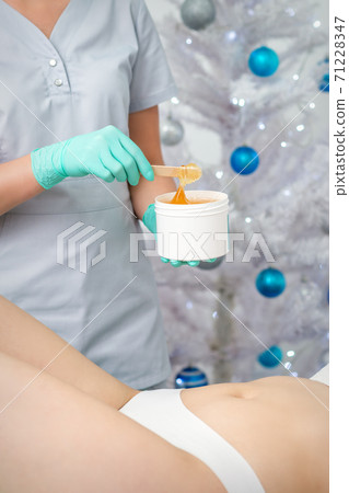 Cosmetologist holds jar with sugaring paste Cosmetologist holds jar with sugaring paste 71228347