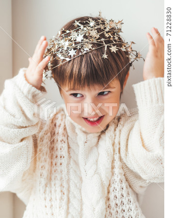 Kid with decorative star tinsel for Christmas tree. Boy in cable-knit oversized sweater. Cozy outfit for snuggle weather. Winter holiday spirit.New year. 71228830