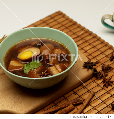 Sweet brown stewed eggs soup (Kai Palo) with pork on bamboo placemat Sweet brown stewed eggs soup (Kai Palo) with pork on bamboo placemat 71229817