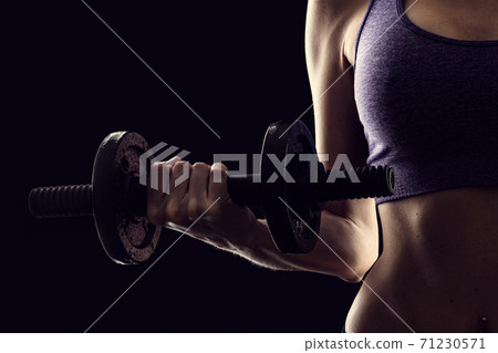Slim athletic woman Holding dumbbell in the hand on black Slim athletic woman Holding dumbbell in the hand on black 71230571