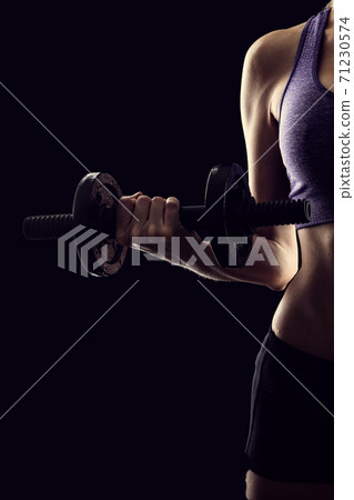 Slim athletic woman Holding dumbbell in the hand on black Slim athletic woman Holding dumbbell in the hand on black 71230574