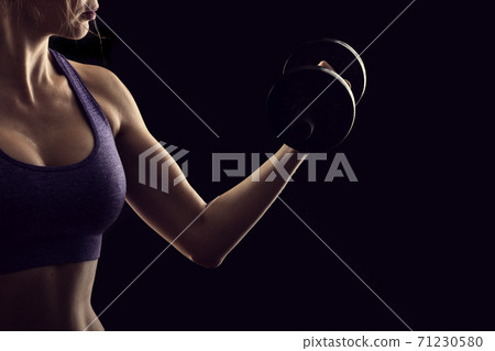 Slim athletic woman Holding dumbbell in the hand on black Slim athletic woman Holding dumbbell in the hand on black 71230580
