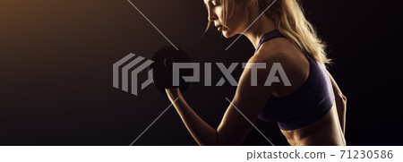 Slim athletic woman Holding dumbbell in the hand on black Slim athletic woman Holding dumbbell in the hand on black 71230586