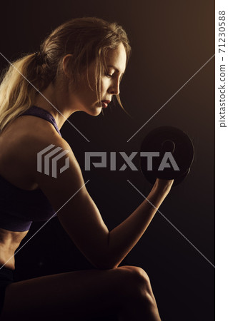 Slim athletic woman Holding dumbbell in the hand on black Slim athletic woman Holding dumbbell in the hand on black 71230588