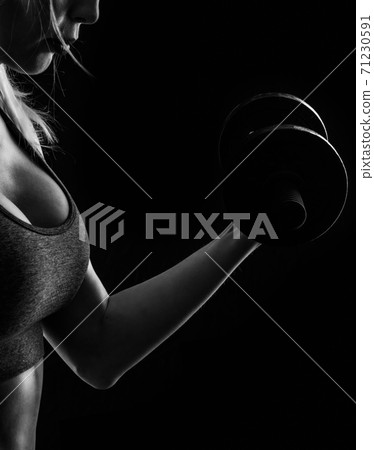 Slim athletic woman Holding dumbbell in the hand on black Slim athletic woman Holding dumbbell in the hand on black 71230591