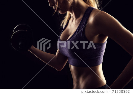 Slim athletic woman Holding dumbbell in the hand on black Slim athletic woman Holding dumbbell in the hand on black 71230592
