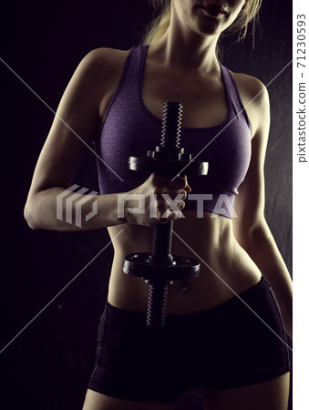 Slim athletic woman Holding dumbbell in the hand on black Slim athletic woman Holding dumbbell in the hand on black 71230593