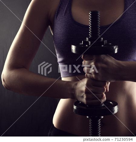 Slim athletic woman Holding dumbbell in the hand on black Slim athletic woman Holding dumbbell in the hand on black 71230594